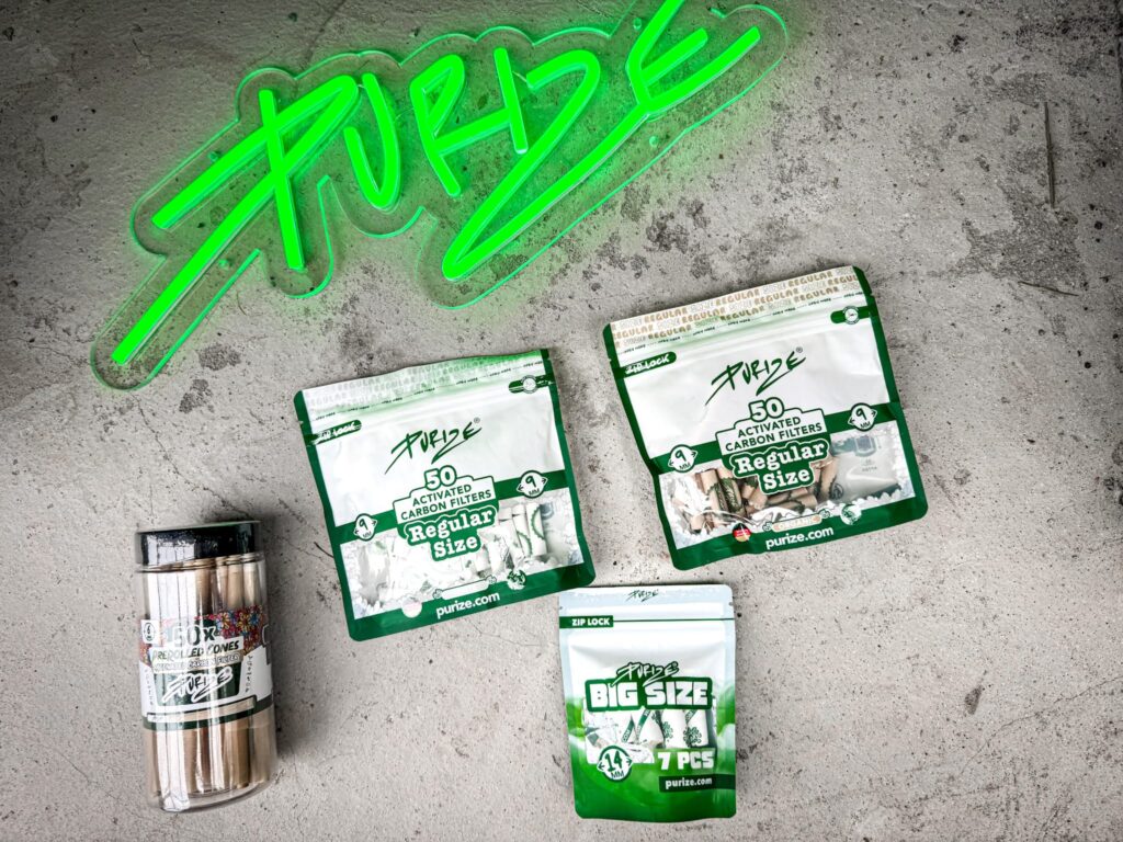 Purize-hiilifiltterit ja pussit betonilattialla vihreän Purize-neonkyltin alla